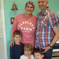 Helen Jones, our Warrior Wednesday spotlight, stands with her husband and three young kids (two boys and a girl) after she rang the bell at her treatment facility.